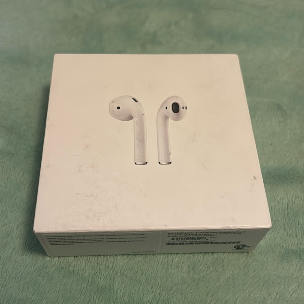 Apple AirPods (1st generation) with charging case and grey silicon cover.